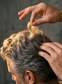 Barber parting a client's hair to read texture before choosing a wax
